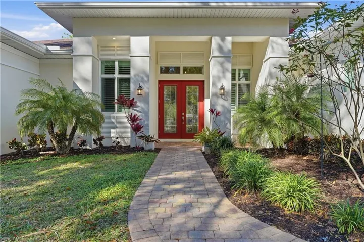 View of exterior entry with lead glass front doors, paver walkway and landscaping