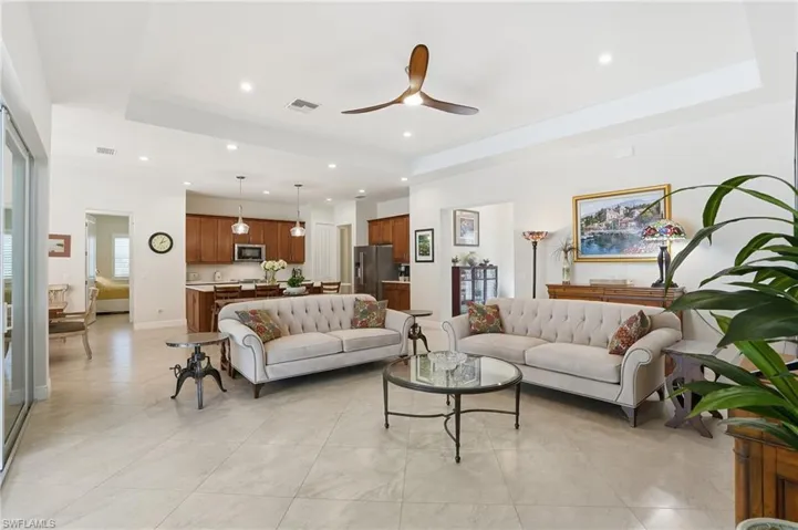 Living room featuring ceiling fan, a tray ceiling, recessed lighting, and light tile patterned floors