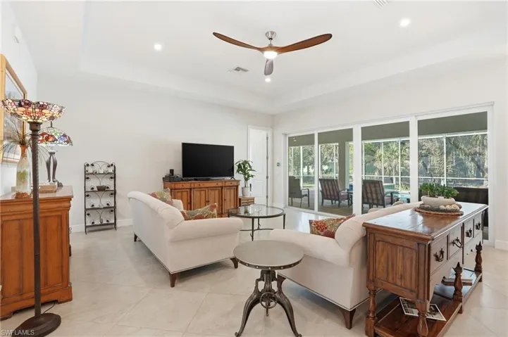 Living room featuring ceiling fan, recessed lighting, a raised ceiling, and light tile patterned floors