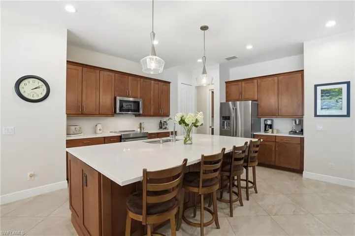 Kitchen with a breakfast bar, pendant lighting, brown cabinetry, and recessed lighting