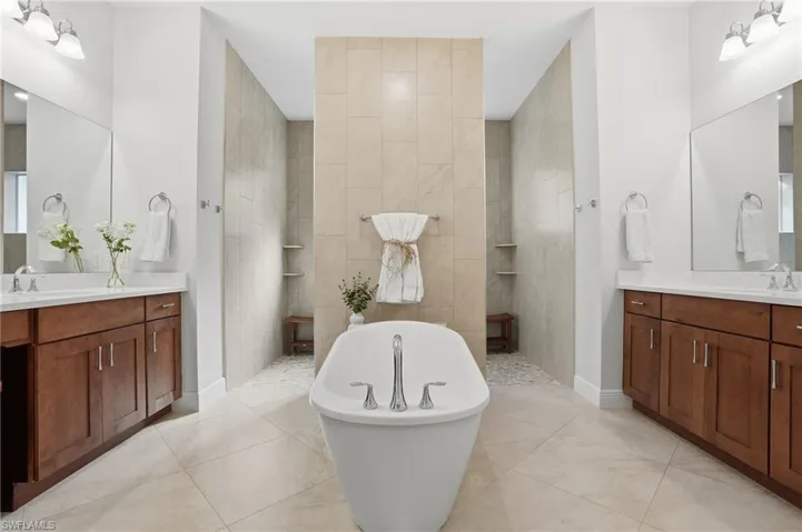 Full bath featuring walk in shower, a soaking tub, and two vanities