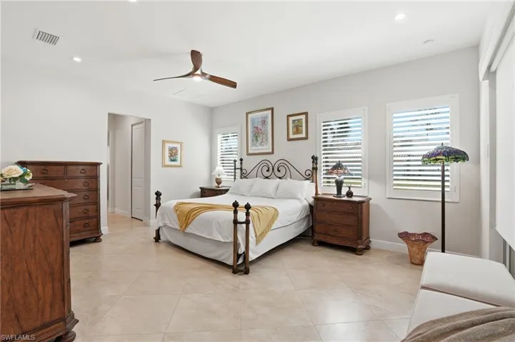 Oversized primary bedroom with space for sitting area, 3 windows dressed with wood plantation shutters for plenty of natural light and electric shades on impact sliders leading to the lanai