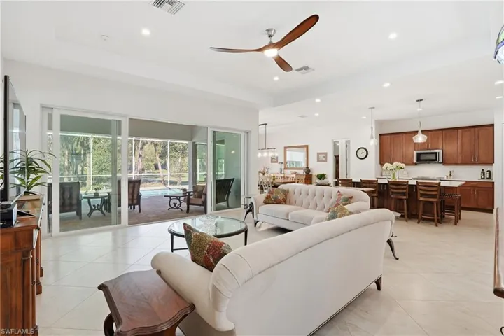 Living room with ceiling fan, recessed lighting, light tile patterned flooring, a tray ceiling, and a sunroom