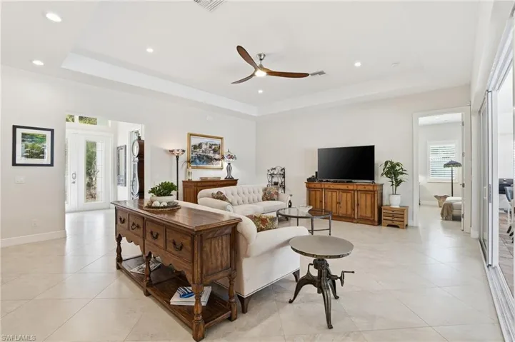 Living area with a ceiling fan, a tray ceiling, recessed lighting, and light tile patterned floors