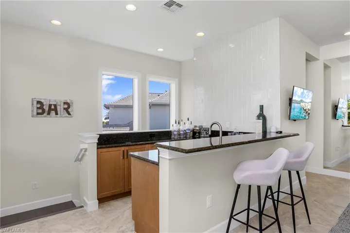 Wet bar, sink, peninsula, and dark stone counters. Your guests will never want to leave!