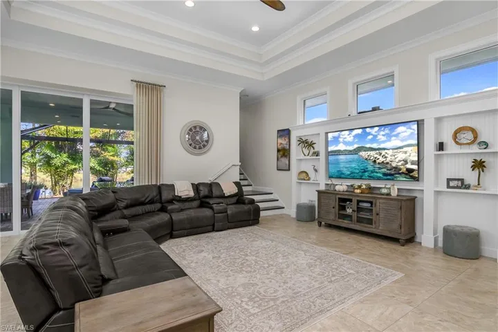 Tiled living room featuring a wealth of natural light, crown molding, built in shelves, and a double tray ceiling ranging from 12 to 14 feet high.