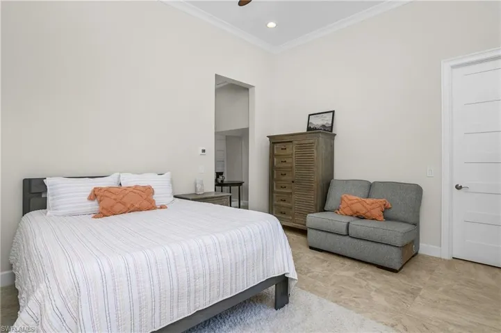 Another view of the ground floor casita Bedroom with tile flooring, ornamental molding and ceiling fan.