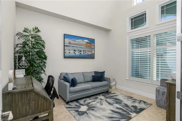 Den featuring a towering ceiling and plenty of natural light.