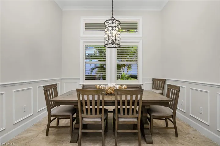 Formal Dining area with ornamental molding and an inviting chandelier. Plantation shutters, crown molding.
