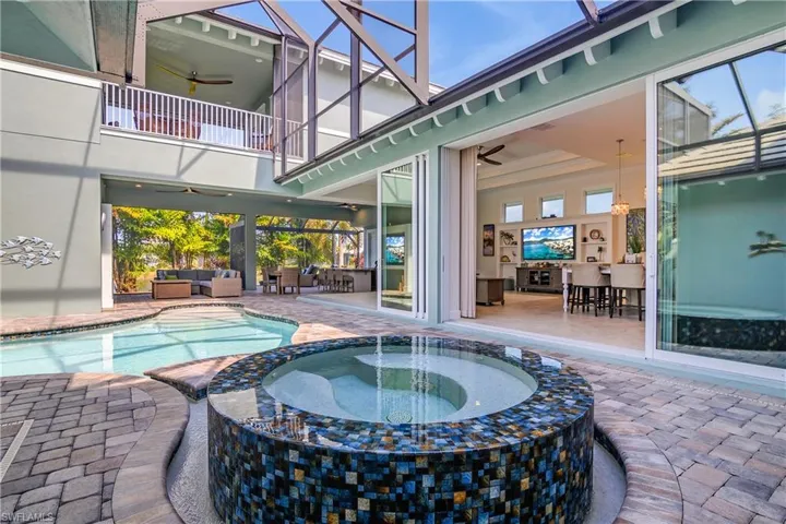 View of pool with an artistic spa attached, an outdoor living space, a lanai, a patio area, and ceiling fan. Note the second floor balcony above. The left side is where the 2nd floor bedroom is located. Right side the Media/Rec Room.
