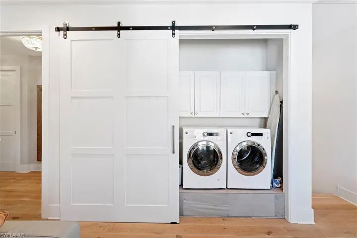 Living room featuring washing machine and clothes dryer, light wood-type flooring, a barn door, and recessed lighting