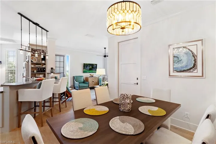 Dining room featuring a chandelier, light wood finished floors, baseboards, and crown molding