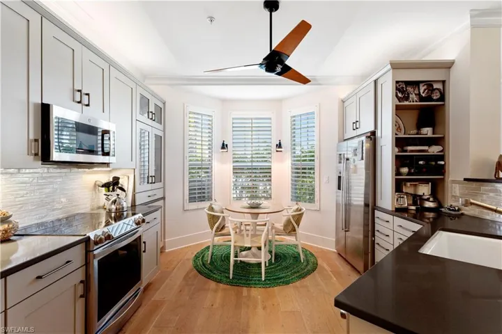 Dining space with light wood finished floors, stairs, a chandelier, baseboards, and a ceiling fan