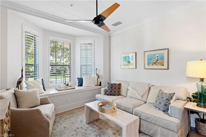 Living room with ceiling fan, ornamental molding, and light wood finished floors
