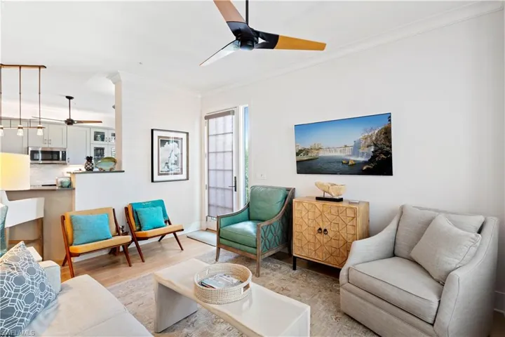 Living room with ceiling fan, crown molding, and light wood-type flooring