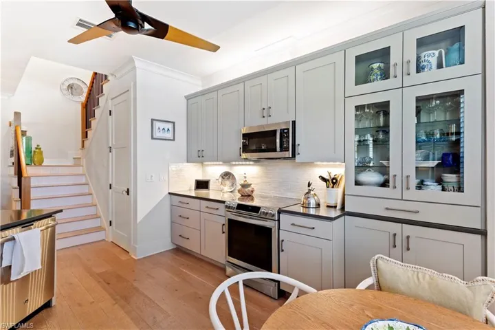 Kitchen featuring stainless steel appliances, ceiling fan, a sink, baseboards, and dark countertops