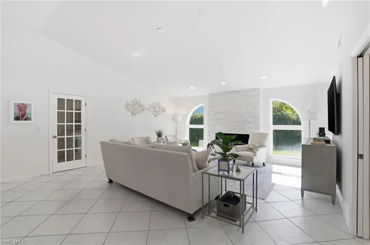 Living area with light tile patterned floors, plenty of natural light, vaulted ceiling, and a large fireplace