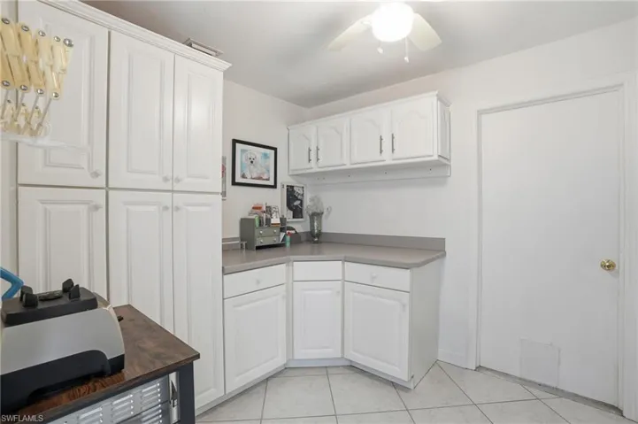 Laundry room with white cabinetry, ceiling fan, and light tile patterned floors