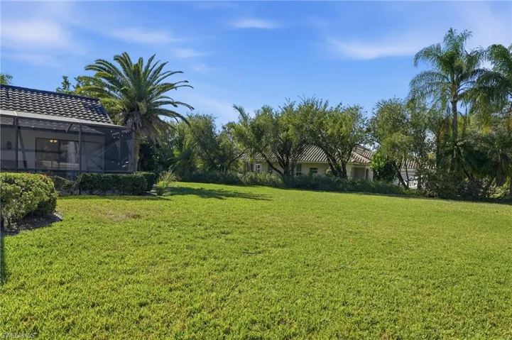 View of grassy yard with glass enclosure and a sunroom