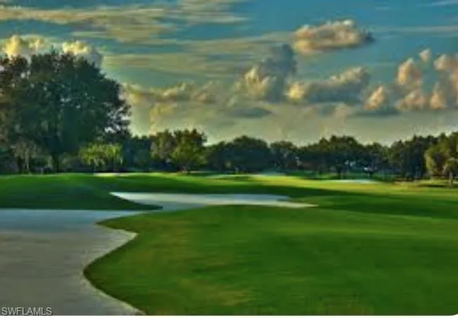 View of community featuring golf course view, a yard, and view of wooded area