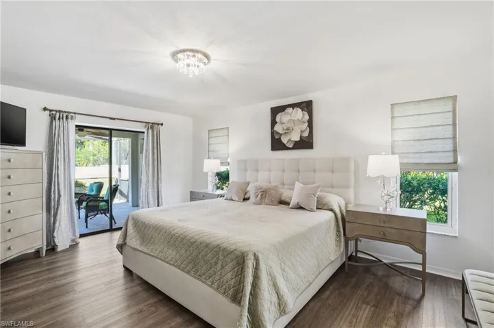 Bedroom with access to exterior, dark wood-style flooring, and a chandelier