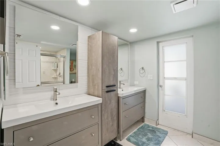 Full bath with a stall shower, light tile patterned flooring, two vanities, and recessed lighting