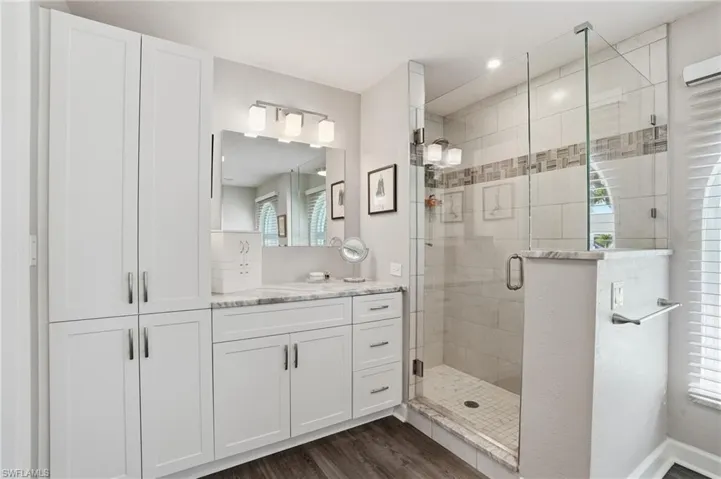 Bathroom with vanity, a shower stall, and dark wood-style flooring