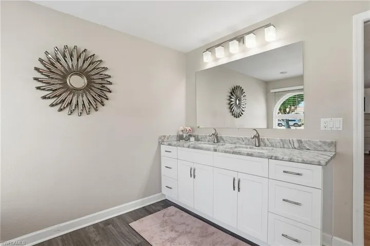 Full bath with double vanity and dark wood-style flooring