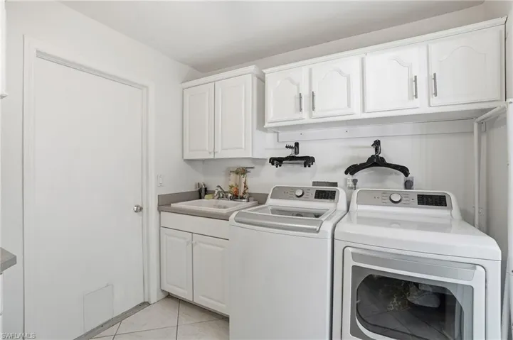 Laundry room featuring light tile patterned floors, independent washer and dryer, and cabinet space