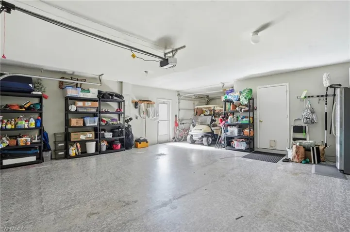 Garage featuring freestanding refrigerator and a garage door opener
