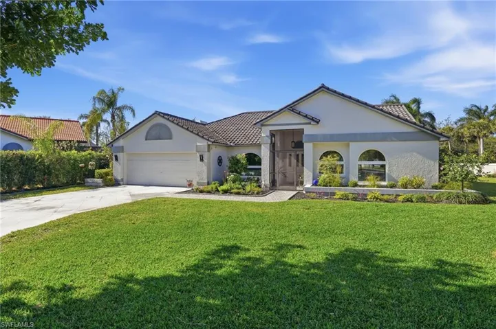 Mediterranean / spanish-style house with driveway, a front lawn, stucco siding, and an attached garage