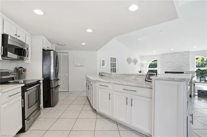 Kitchen featuring stainless steel appliances, white cabinets, light stone countertops, recessed lighting, and light tile patterned floors