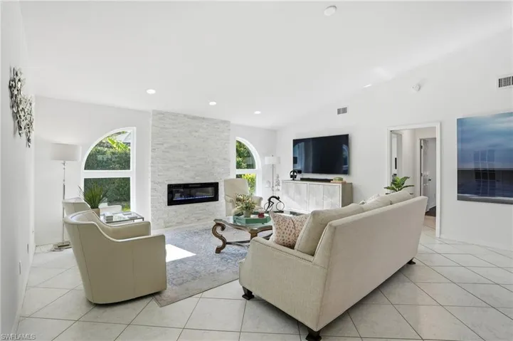 Living room featuring light tile patterned floors, a fireplace, recessed lighting, and high vaulted ceiling