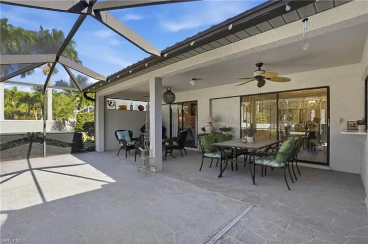 View of patio with outdoor dining area, a sunroom, a ceiling fan, and glass enclosure