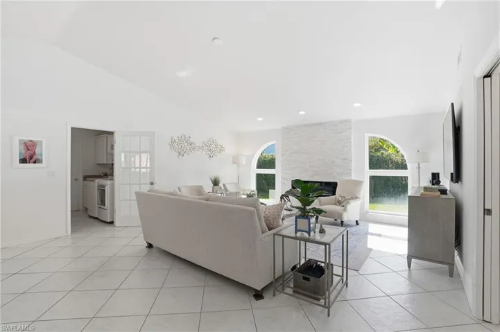 Living area featuring healthy amount of natural light, a fireplace, light tile patterned floors, and high vaulted ceiling