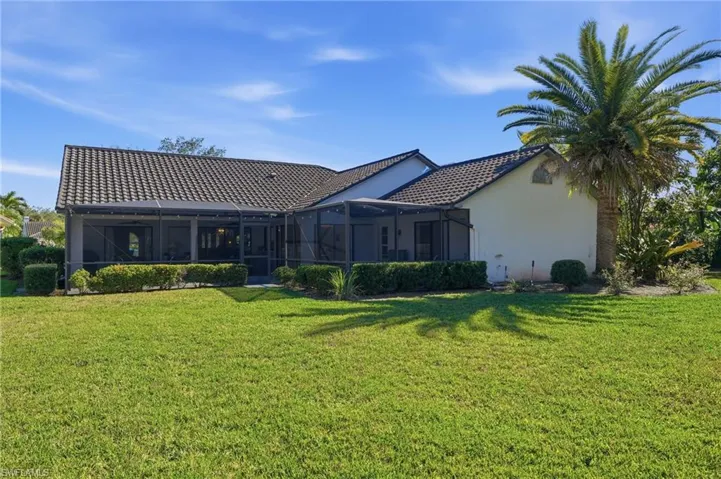 Back of house featuring a lanai, a lawn, a sunroom, and a tiled roof