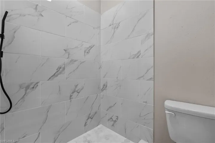 Full bath with tiled shower and toilet