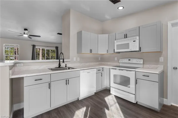 Kitchen with white appliances, light countertops, and dark wood-style floors