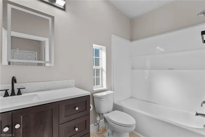 Full bath featuring vanity, bathtub / shower combination, and decorative backsplash