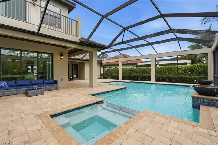 Expansive screened lanai featuring a rectangular swimming pool, integrated spa, and paver patio