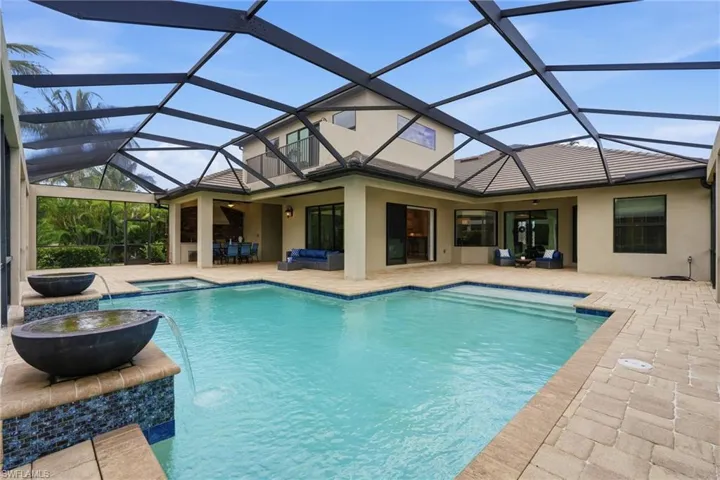 Expansive screened lanai featuring a swimming pool, integrated spa, and dual water features