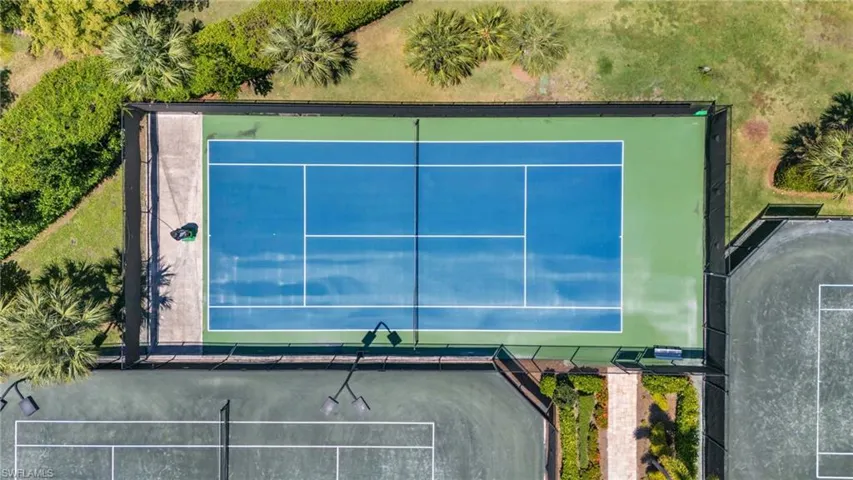 Regulation-size tennis court featuring a blue playing surface with green surrounds