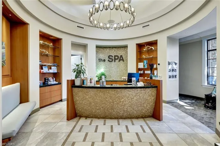 Curved reception area featuring a textured front desk, wood-finish shelving, and a mosaic wall accent
