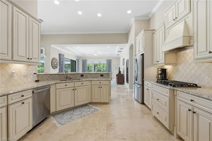 Kitchen featuring light-toned cabinetry, granite countertops, stainless steel appliances, and a tiled backsplash