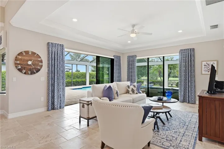 Living area featuring a tray ceiling with recessed lighting and a ceiling fan