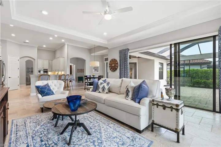 Spacious living area featuring neutral wall tones, crown molding, recessed lighting, and tile flooring