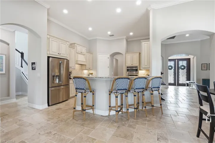 Open-concept kitchen featuring light cabinetry, stainless steel appliances, and a breakfast bar