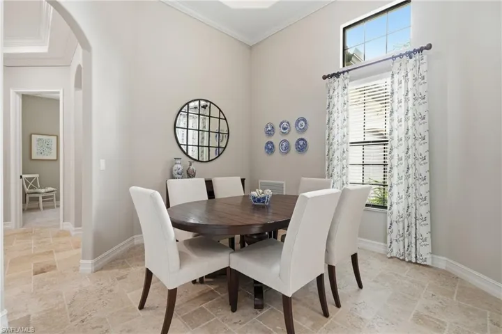 Formal dining area featuring vaulted ceilings, arched doorways, a transom window, and light-toned tile flooring