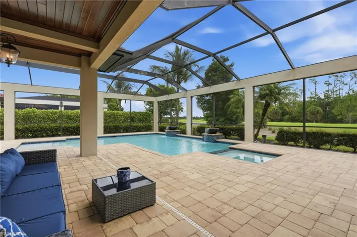 Screened lanai featuring a swimming pool, integrated spa, and paver decking
