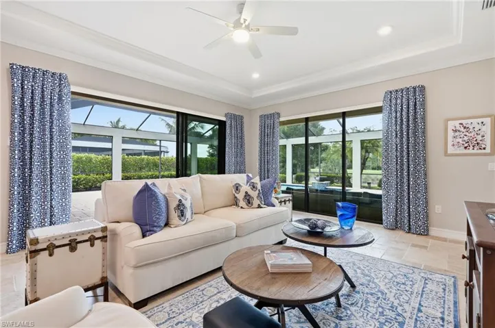 Living area featuring expansive glass sliding doors, tray ceiling, recessed lighting, and a ceiling fan